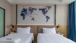 Ett hotellrum med två sängar, en världskarta på väggen och ett fönster med gardiner.