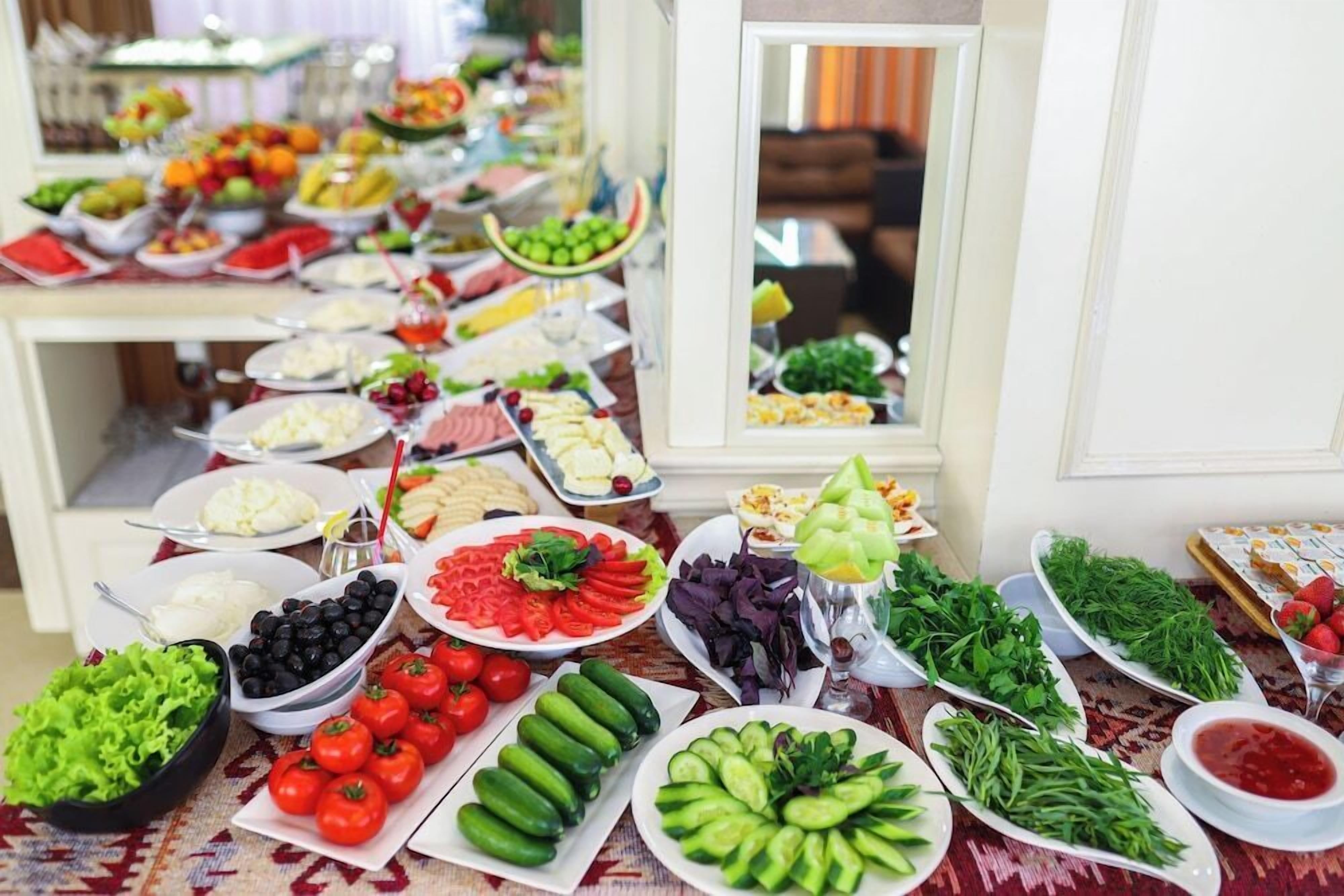 A buffet with a variety of food items including fruits, vegetables, and salads.