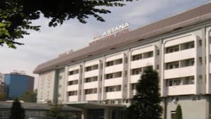 A multi-story building with the name "ASTANA" on the facade, featuring a symmetrical design with evenly spaced windows and a flat roof. - Astana International (Almaty)