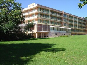 A multi-story hotel with a flat roof, balconies, and a large lawn area. - Gloria Saints Constantine And Helena (Varna)