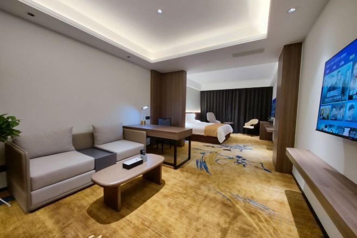 Una habitación de hotel con sofá, mesa de centro, escritorio y cama.