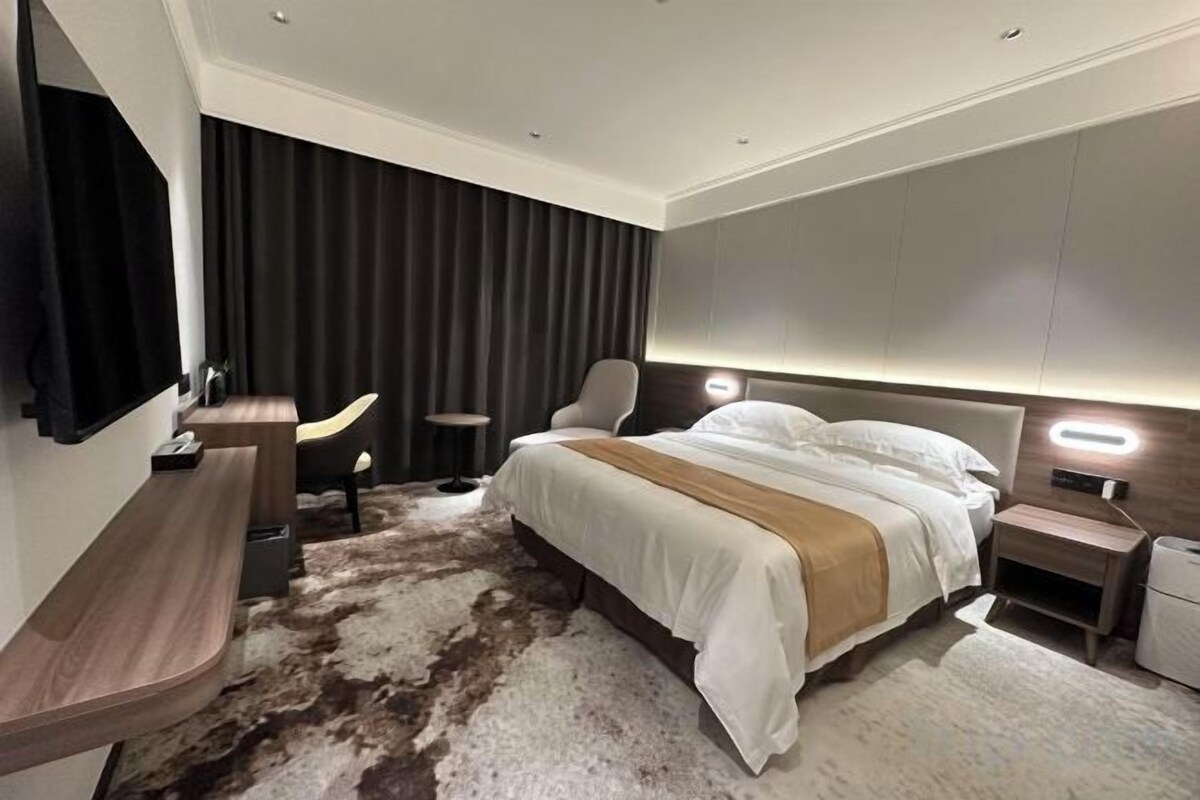 Habitación de hotel moderna con una cama grande, un escritorio, una silla y una mesita.