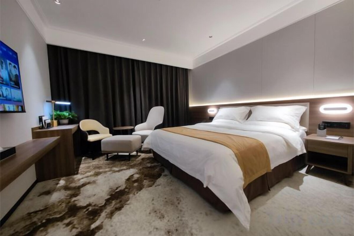 Una habitación de hotel moderna con una cama grande, un escritorio, una silla y un televisor.