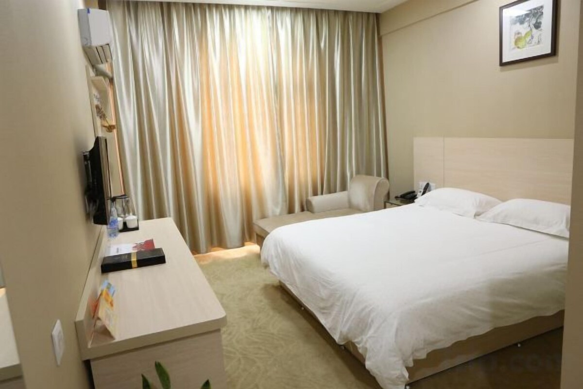 Una habitación de hotel con una cama, un escritorio, una silla, un teléfono y una cortina.