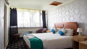 Een hotelkamer met een bed, een televisie, een bureau en een raam met gordijnen.