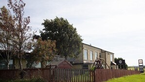 Een woonwijk met een huis, een schommel en een omheining.