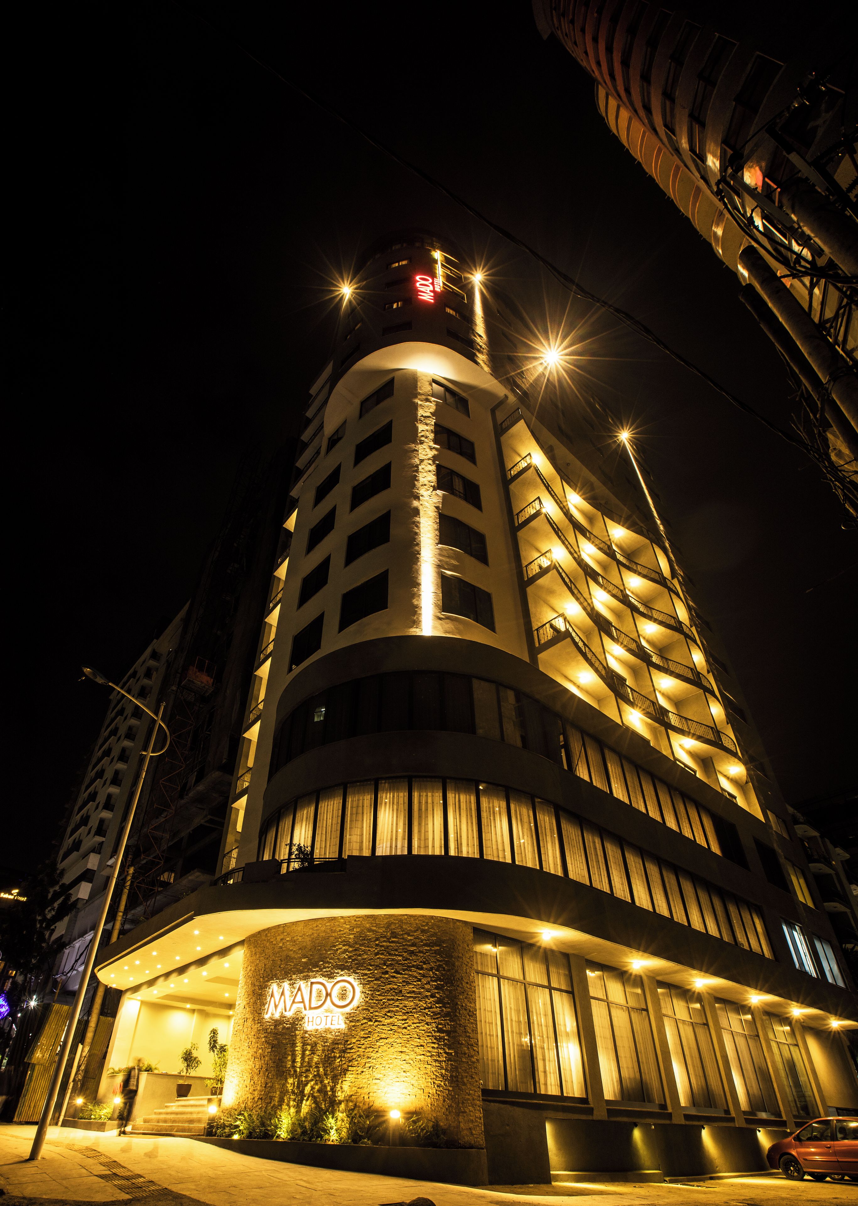 A modern hotel with a curved facade, illuminated signage, and a prominent entrance.