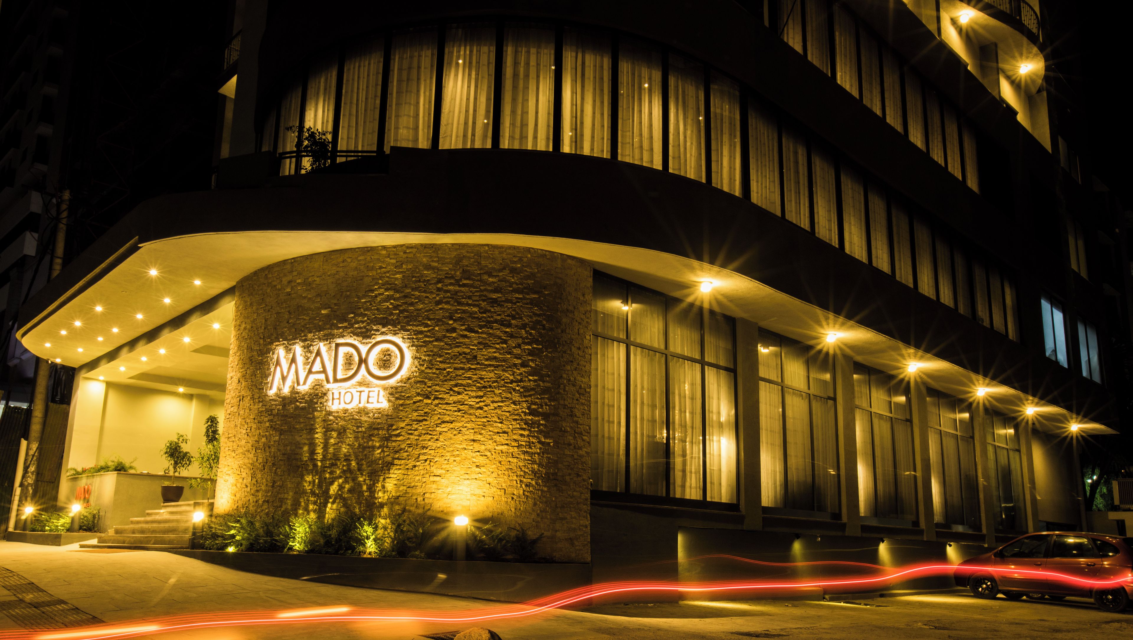 A modern hotel with a curved facade, illuminated signage, and a well-lit entrance.