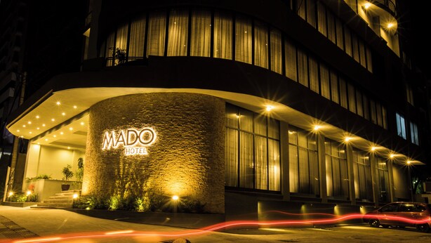 Un hotel moderno con fachada curva, señalización iluminada y una entrada bien iluminada.