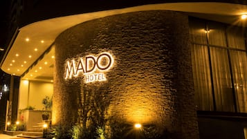 A hotel entrance with a stone facade and illuminated signage.