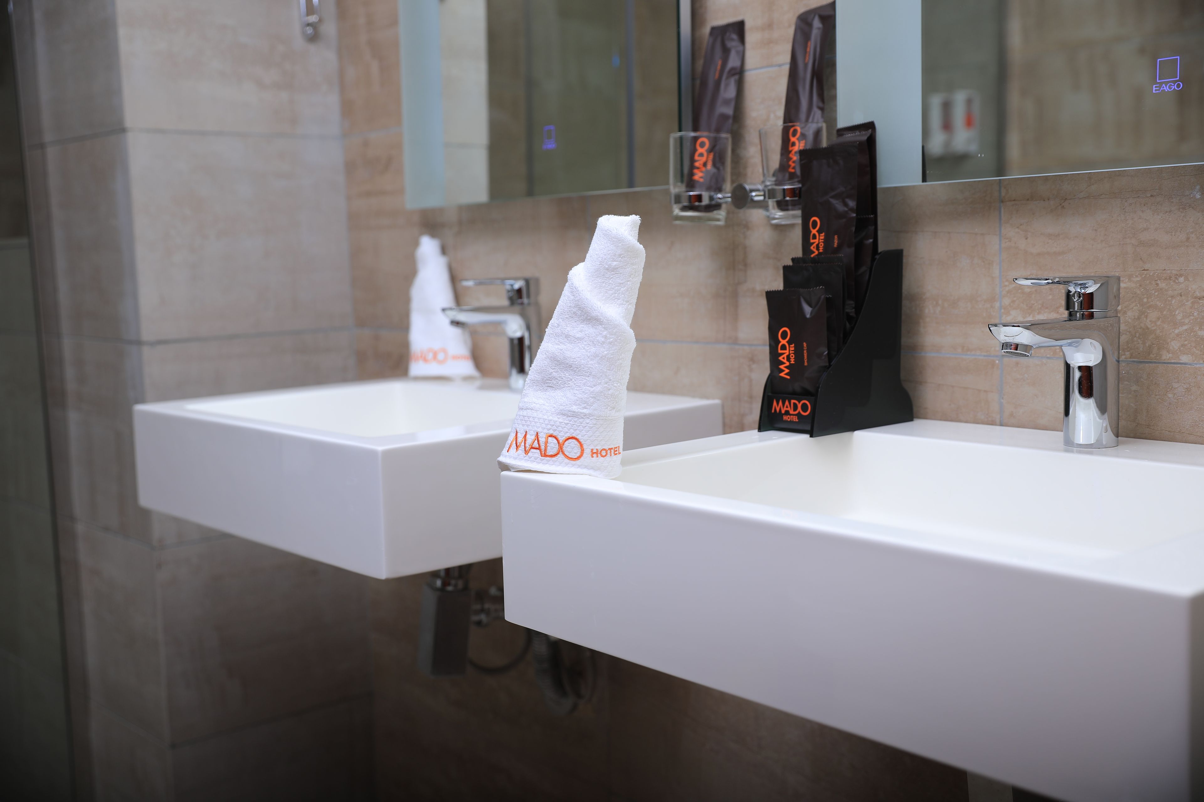 Une salle de bain d’hôtel avec deux lavabos, un distributeur de serviettes et un miroir.