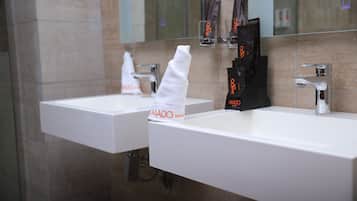 Une salle de bain d’hôtel avec deux lavabos, un distributeur de serviettes et un miroir.