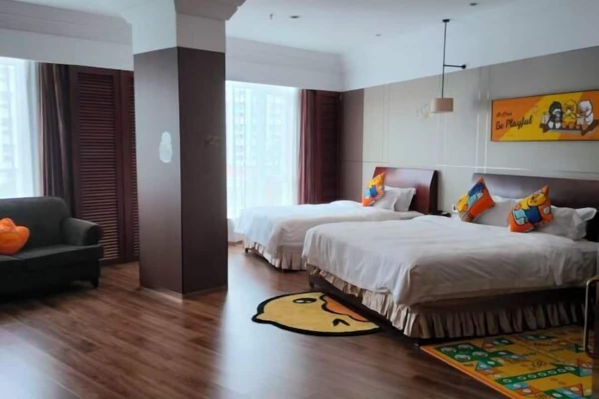 A hotel room with two beds, a sofa, a large window, and a colorful rug.