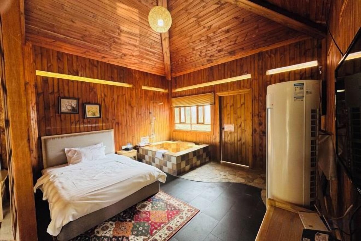 A wooden room with a bed, a bathtub, and a heater.