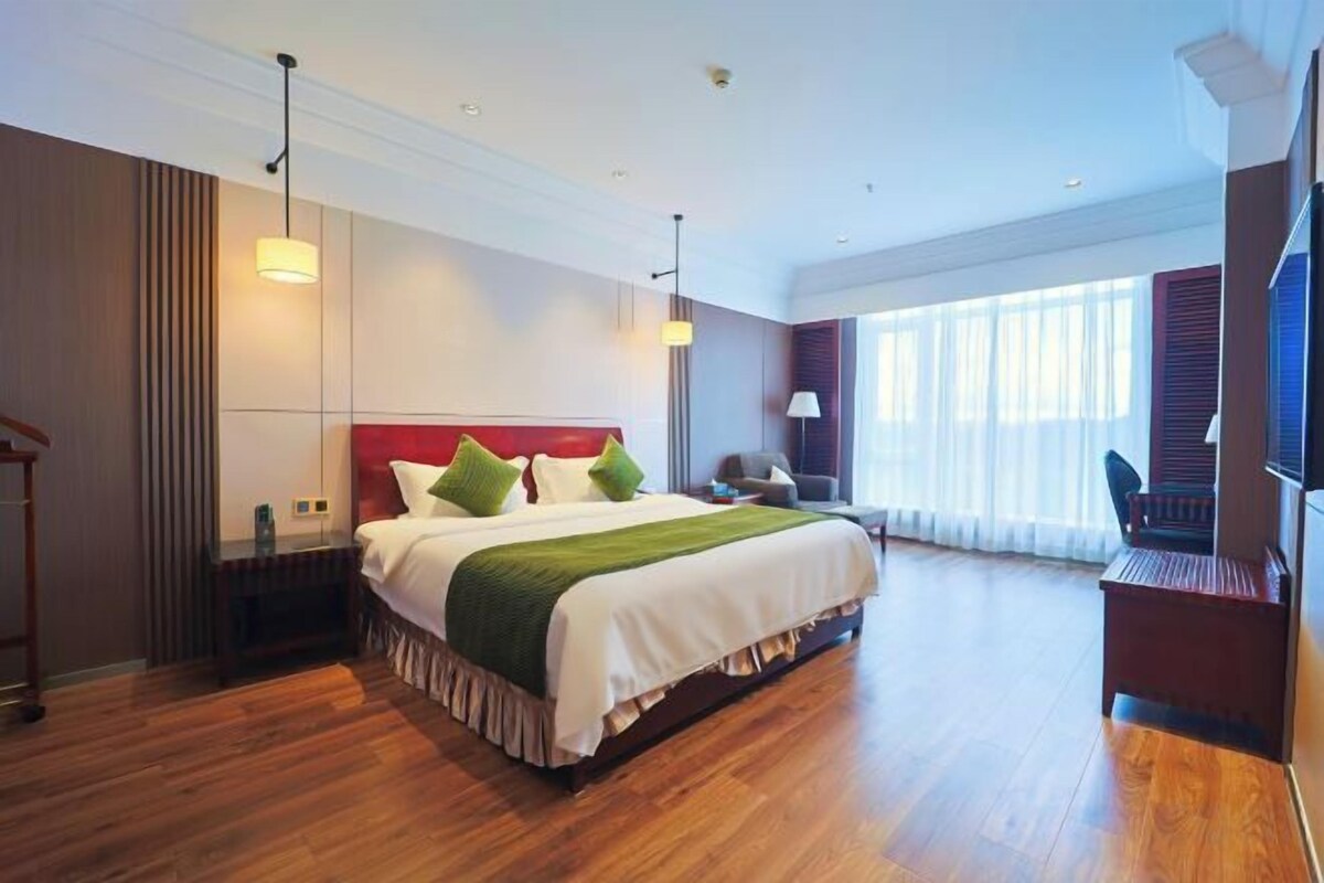 A hotel room with a large bed, a desk, and a television.