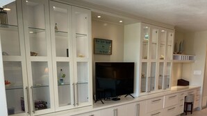 A modern living room with a large TV, built-in cabinets, and a patterned rug.