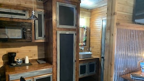 Una cocina rústica con armarios de madera, un microondas integrado y un lavabo.