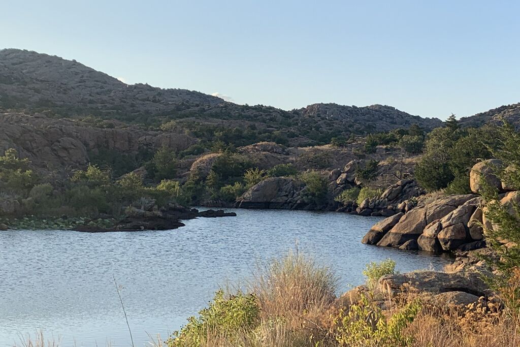 A natural landscape with a body of water surrounded by rocky terrain and sparse vegetation.