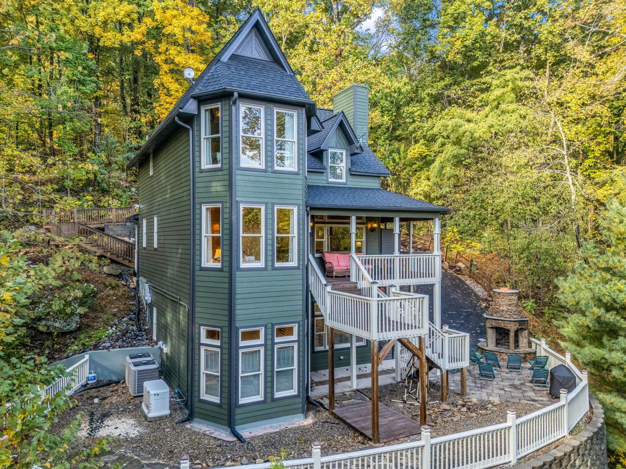 A two-story house with a balcony, surrounded by trees.