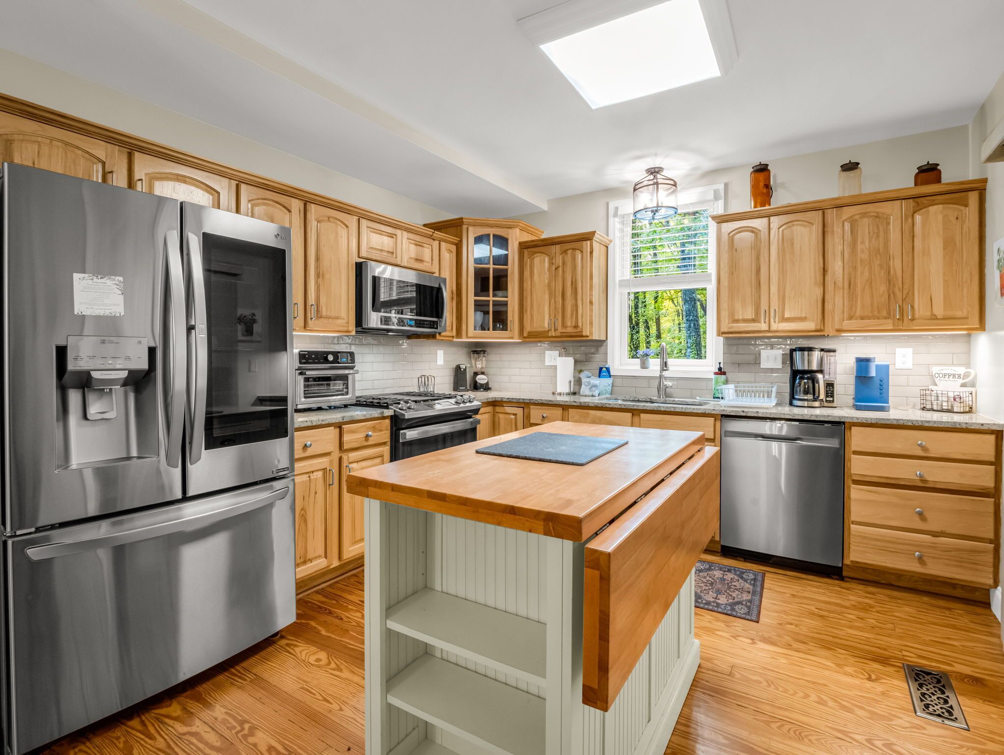 A modern kitchen with stainless steel appliances, wooden cabinets, and a central island.