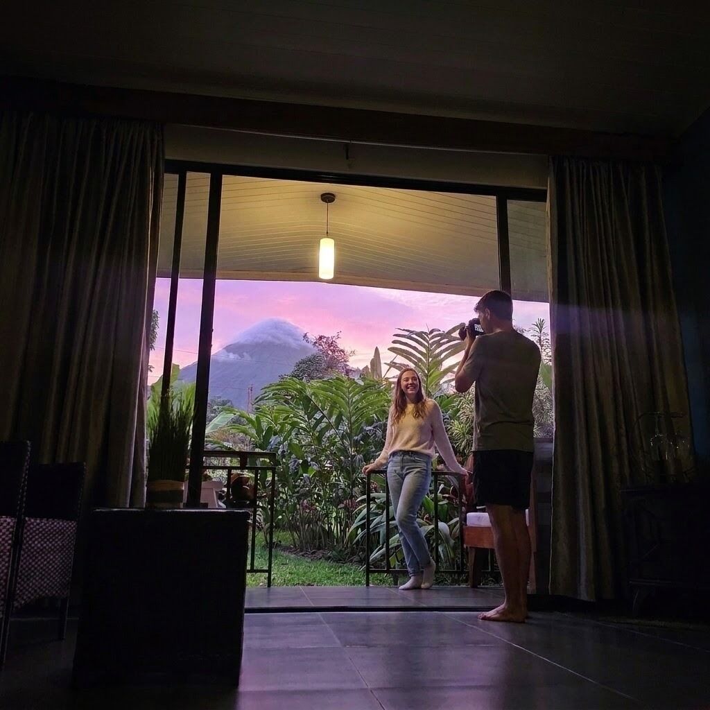 A room with a large sliding glass door leading to a garden, a ceiling light, and a person taking a photo.