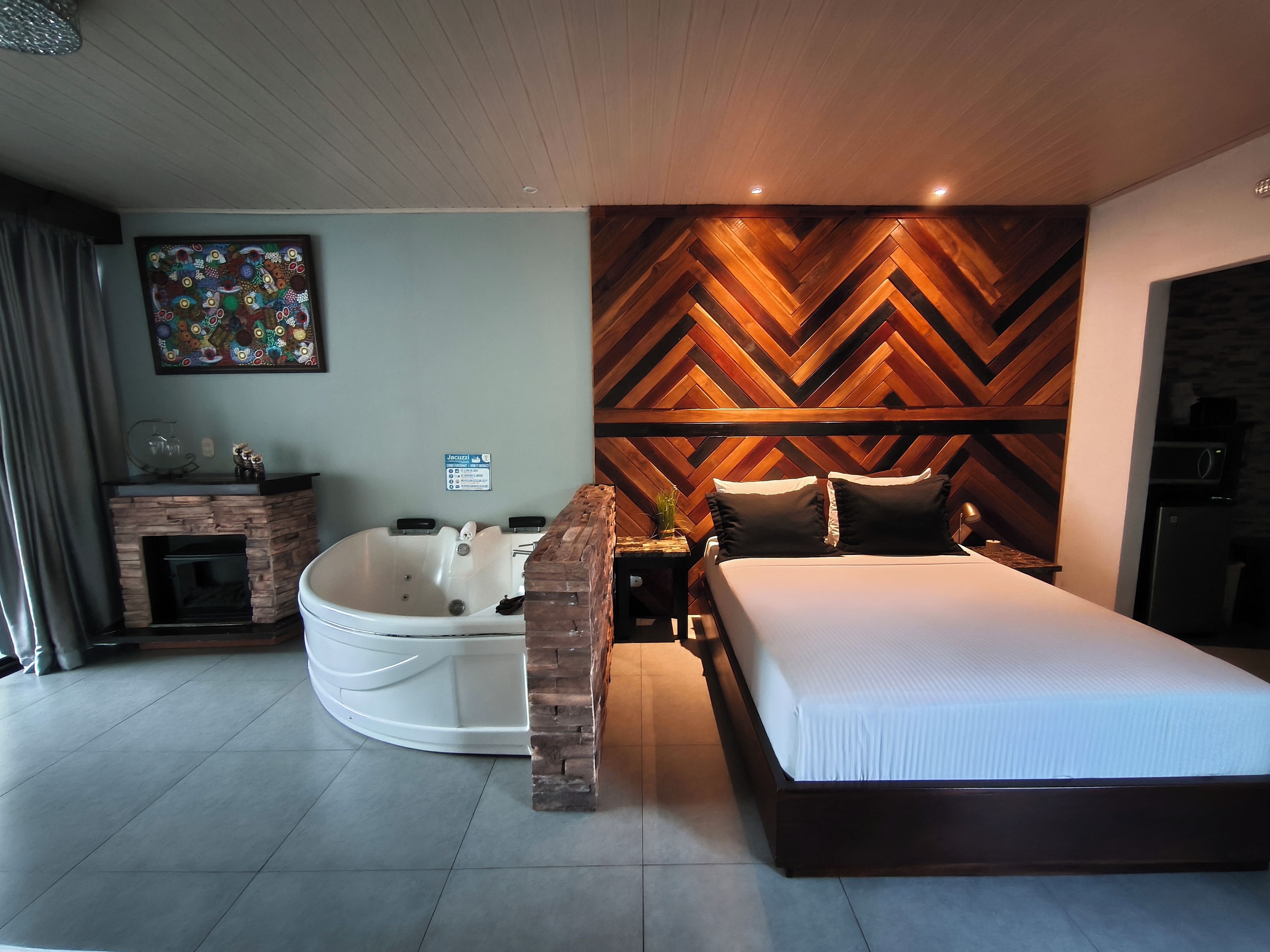 Un dormitorio moderno con una cama grande, un jacuzzi integrado y una pared de madera con diseño en espiga.