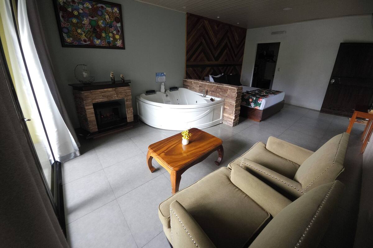 A living room with a fireplace, a large tub, a sofa, and a painting on the wall.