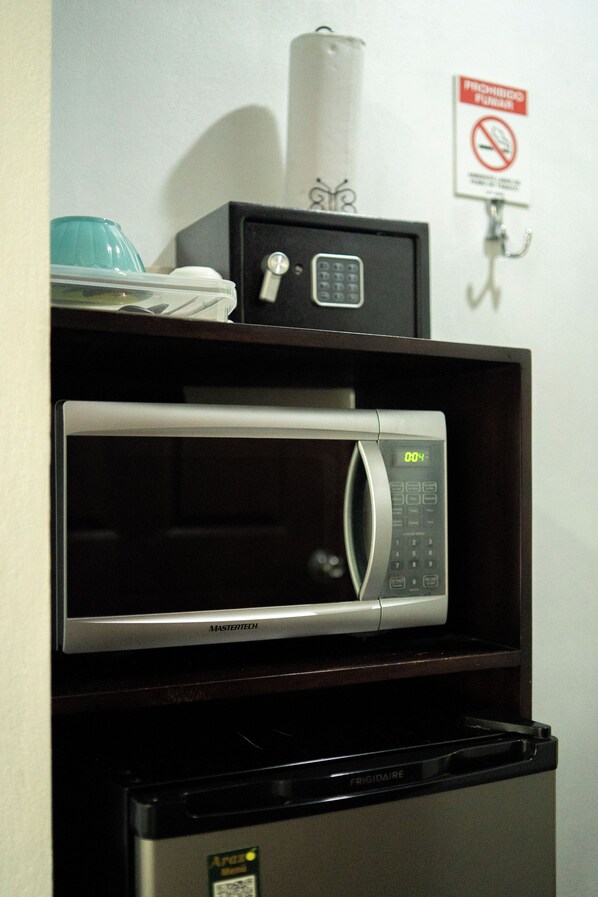 A compact kitchen with a microwave and a refrigerator. - Yellow Tree Suites (La Fortuna)