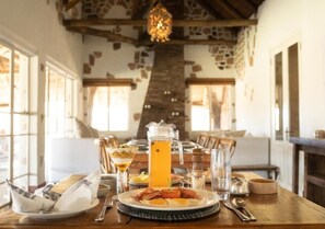 A dining table with a pitcher of orange juice, plates of food, and cutlery.