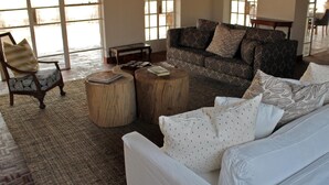 Un salon spacieux avec une grande fenêtre, un canapé à motifs, un canapé blanc et une table basse en bois.