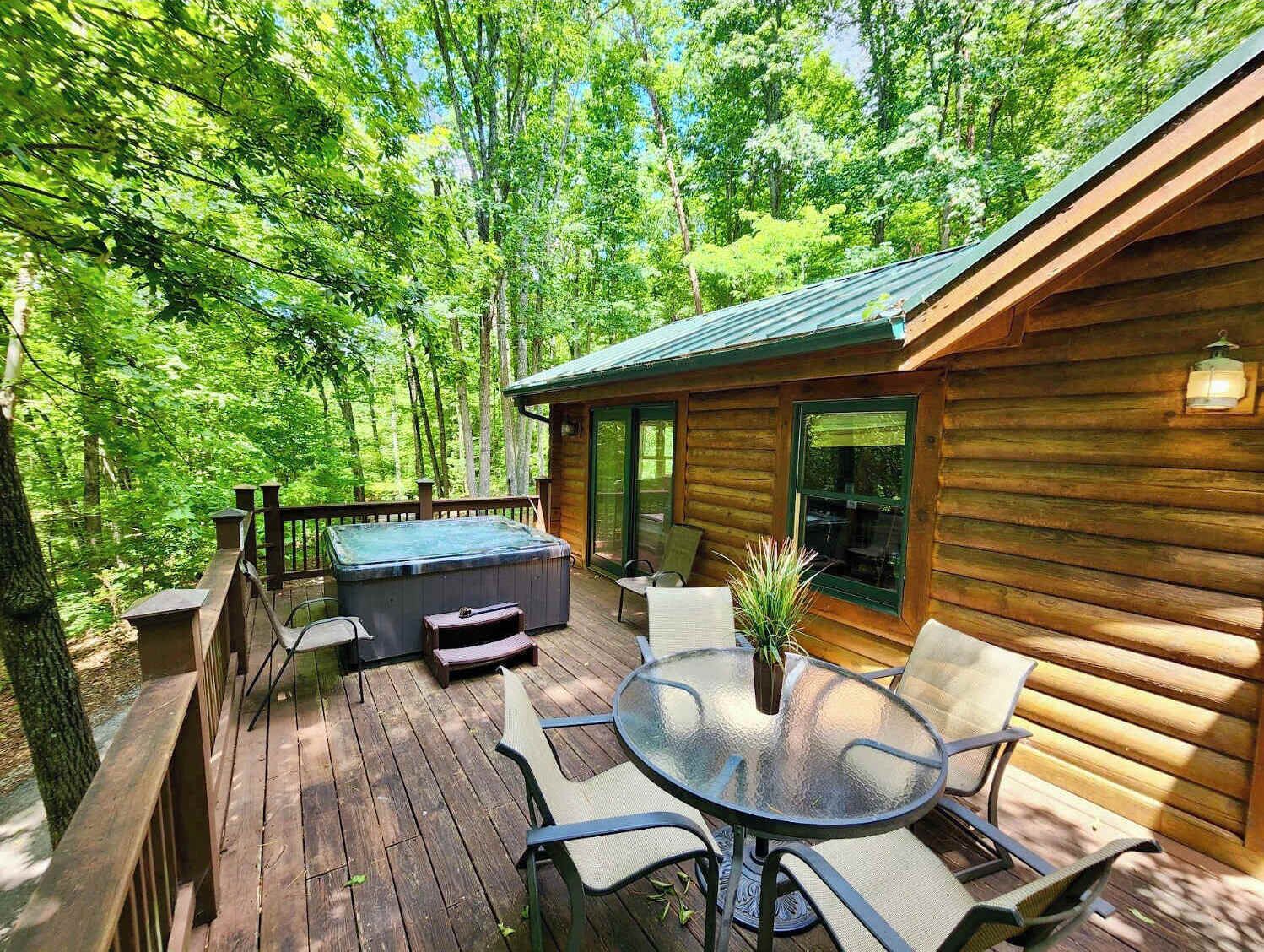 A wooden cabin with a hot tub, deck chairs, and a glass table.