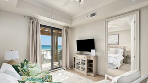 Una habitación amplia con una cama grande, televisión y balcón con vista al mar.