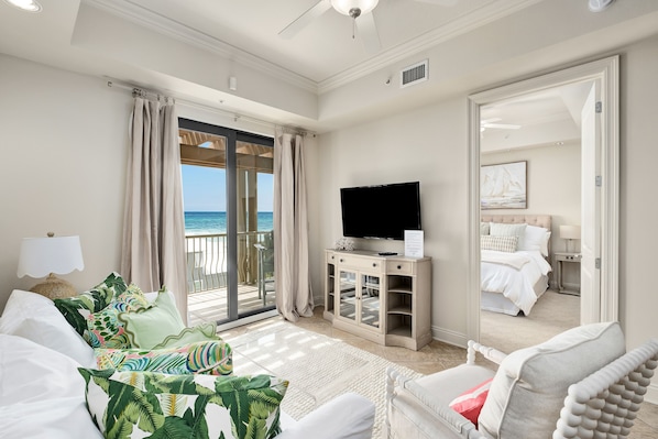 A spacious room with a large bed, a television, and a balcony with a view of the sea. - Top floor 2 BR/2BA in Abacos, Incredible Views and Luxurious Design (Santa Rosa Beach)