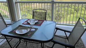 A table set with a glass, plate, and napkin on a balcony overlooking a coastal landscape. - Newly renovated Bayfront Condo, Beach Club, Pools, Hot Tubs, Sunsets and More!! (Galveston)