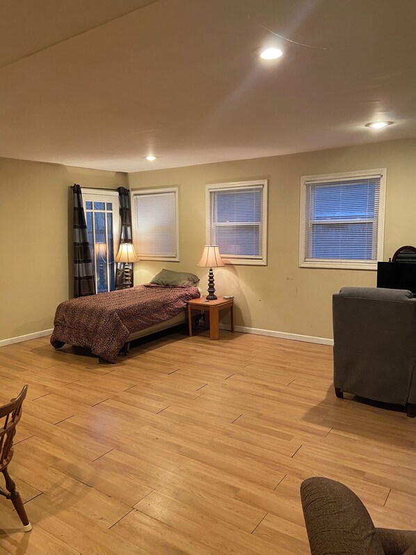 A bedroom with a bed, two bedside tables, a lamp, a chair, and a couch.