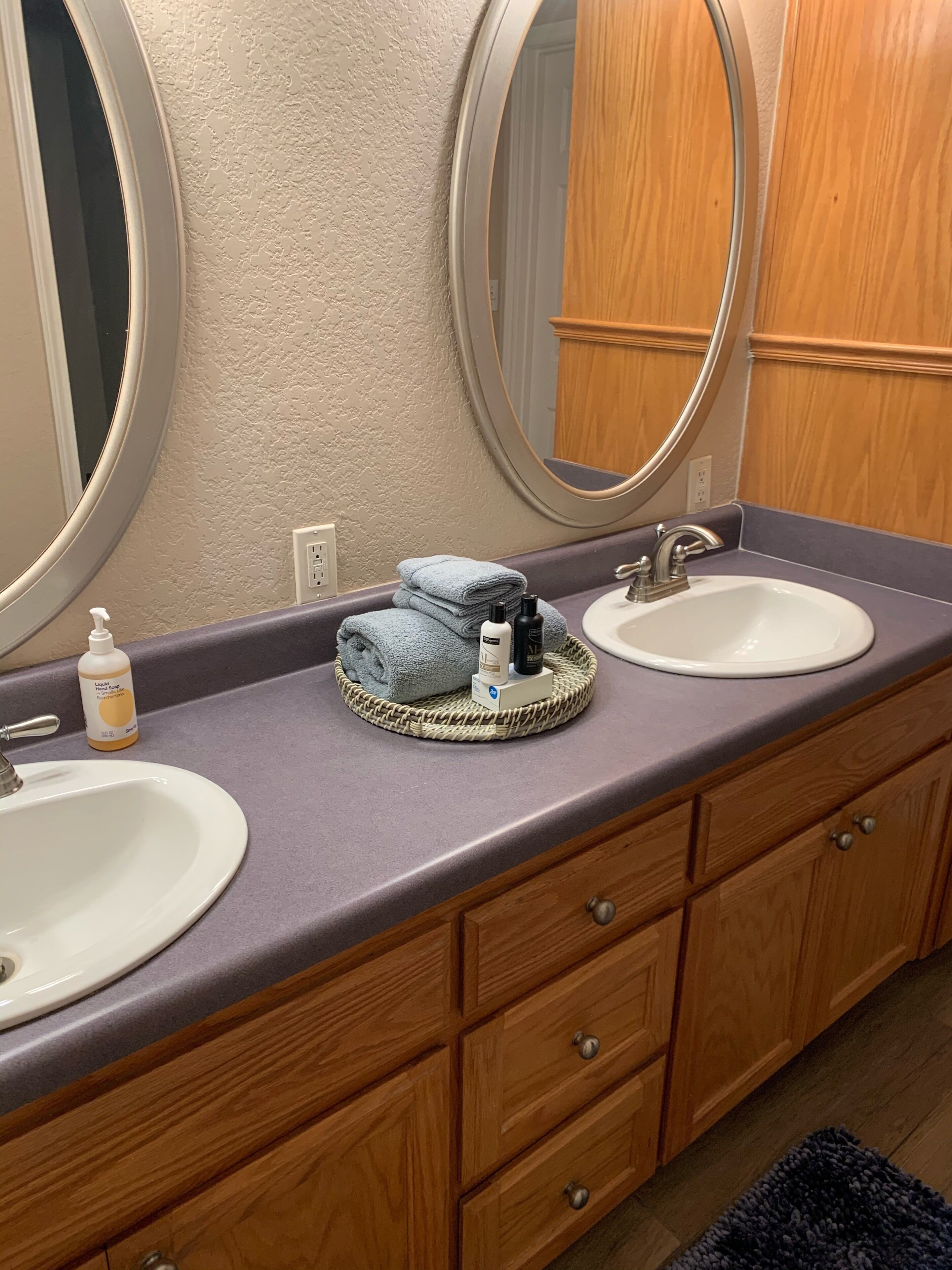 Un bagno con due lavandini, uno specchio e un mobile da bagno in legno con cassetti.