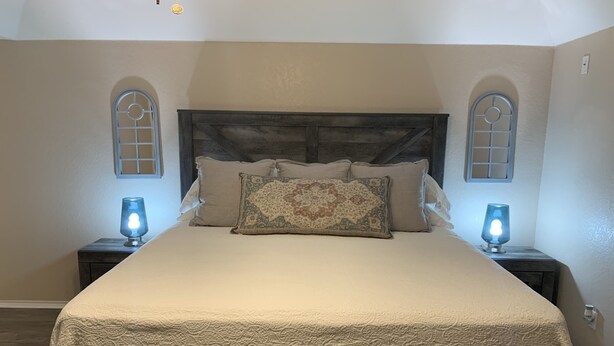 Een slaapkamer met een groot bed, twee bedlampen en een decoratief hoofdeinde.