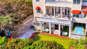 Un bâtiment à deux étages, doté d’un toit recouvert de tuiles rouges, d’un balcon avec des sièges d’extérieur et d’une piscine.