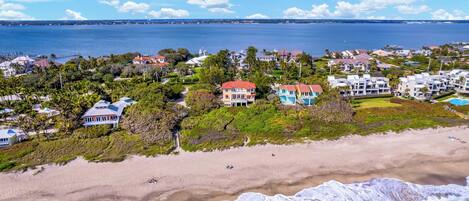 Zona residencial costera con propiedades frente al mar, un puerto deportivo y una vista despejada del océano.
