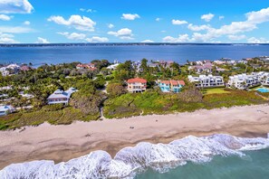 A coastal residential area with beachfront properties, a marina, and a clear view of the ocean.
