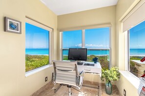 Ein Zimmer mit Schreibtisch, Computer und Meerblick.