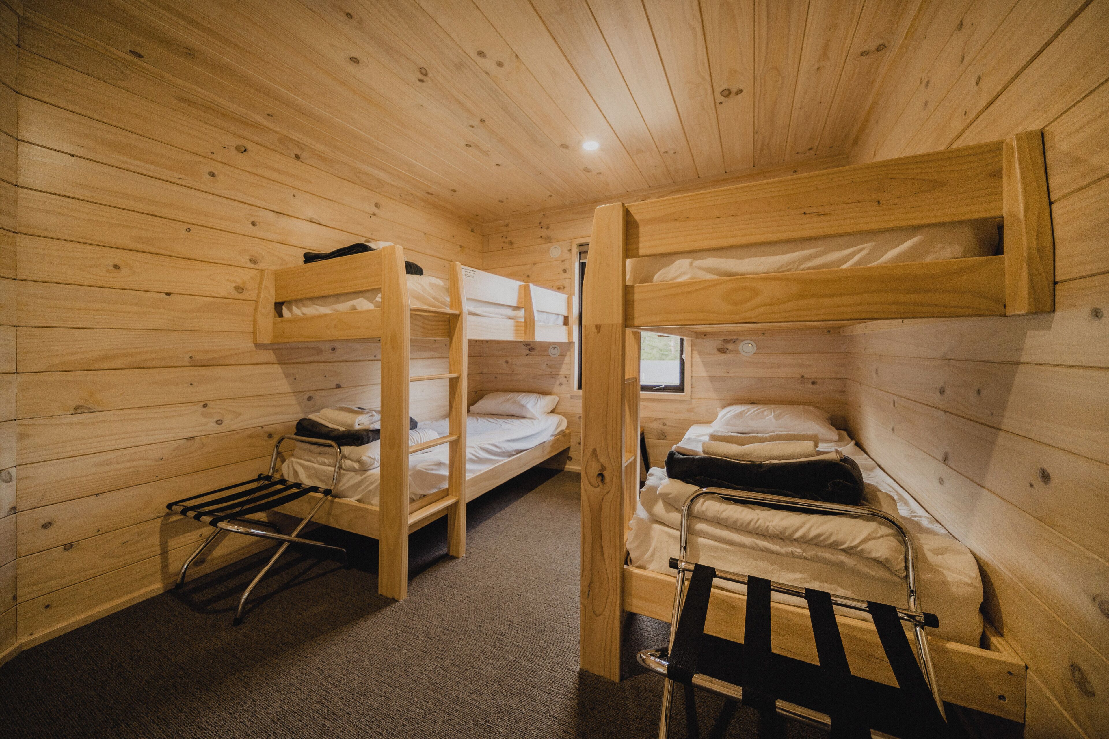 A wooden cabin with bunk beds, a small window, and a metal drying rack.