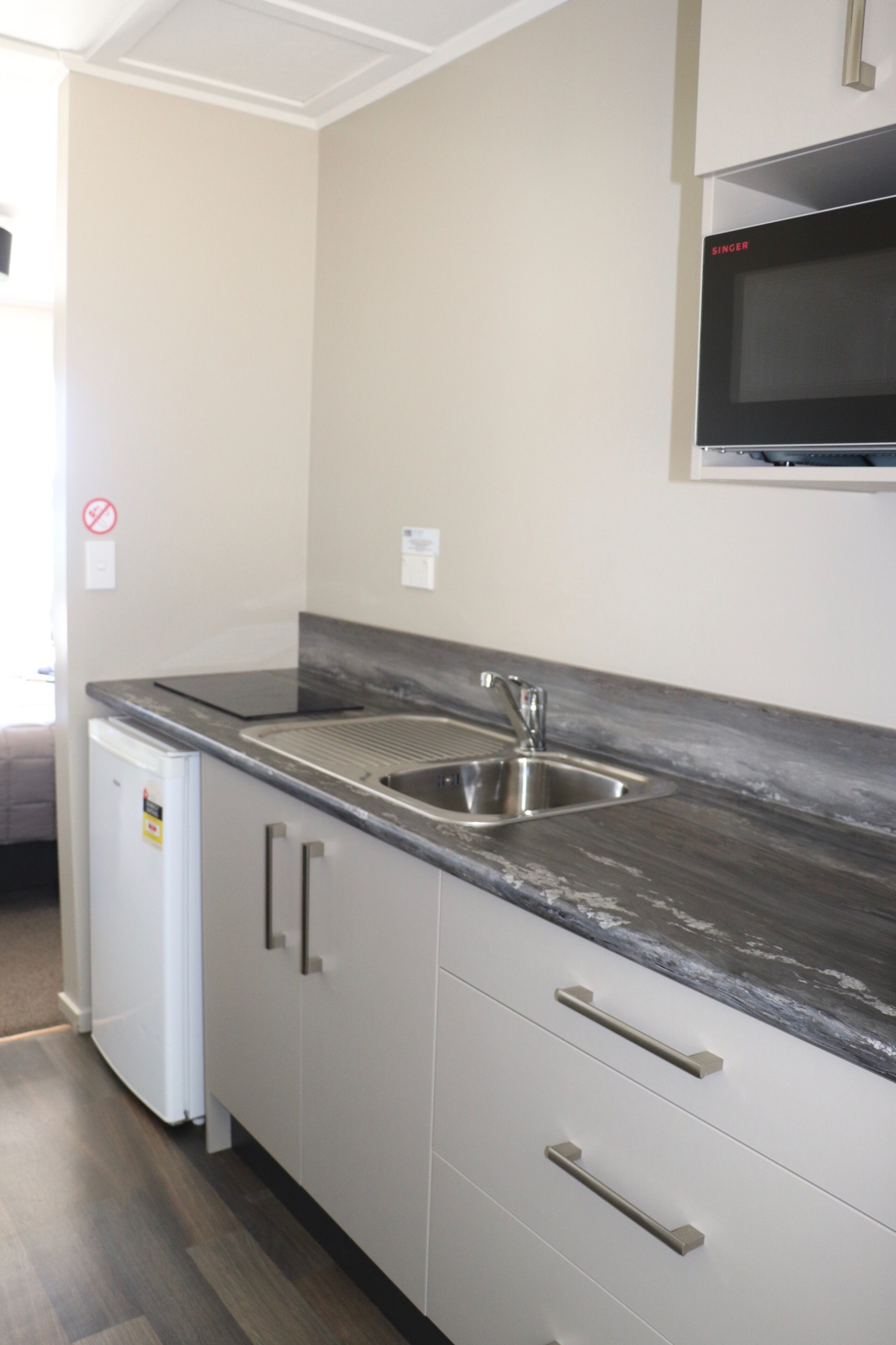 A compact kitchen with a built-in sink, a microwave, and a small refrigerator.