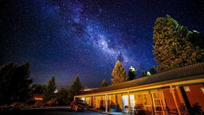 A building with a covered outdoor area, a car parked in front, and a starry night sky.