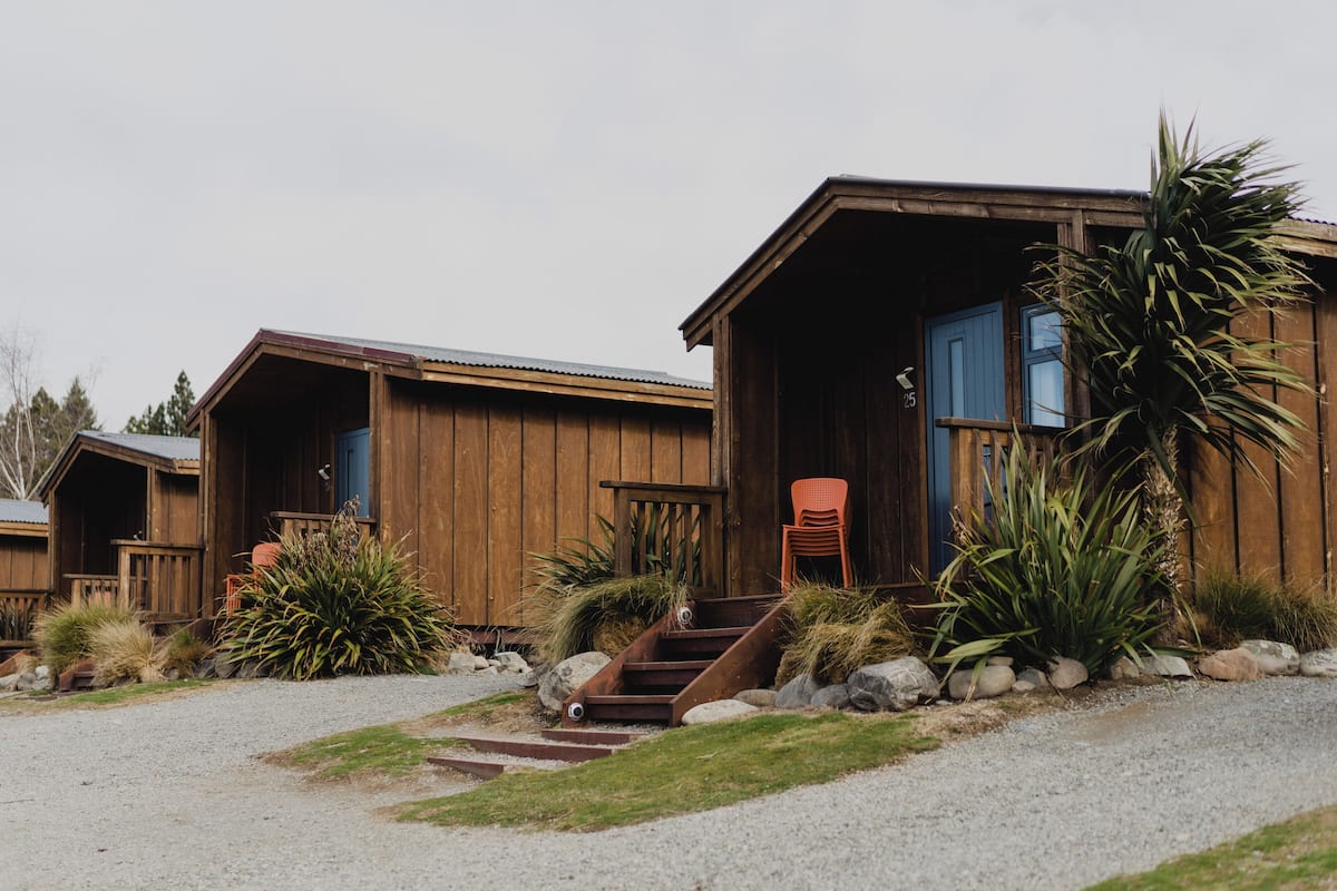 A wooden cabin with a porch, steps leading to the entrance, and a chair outside.