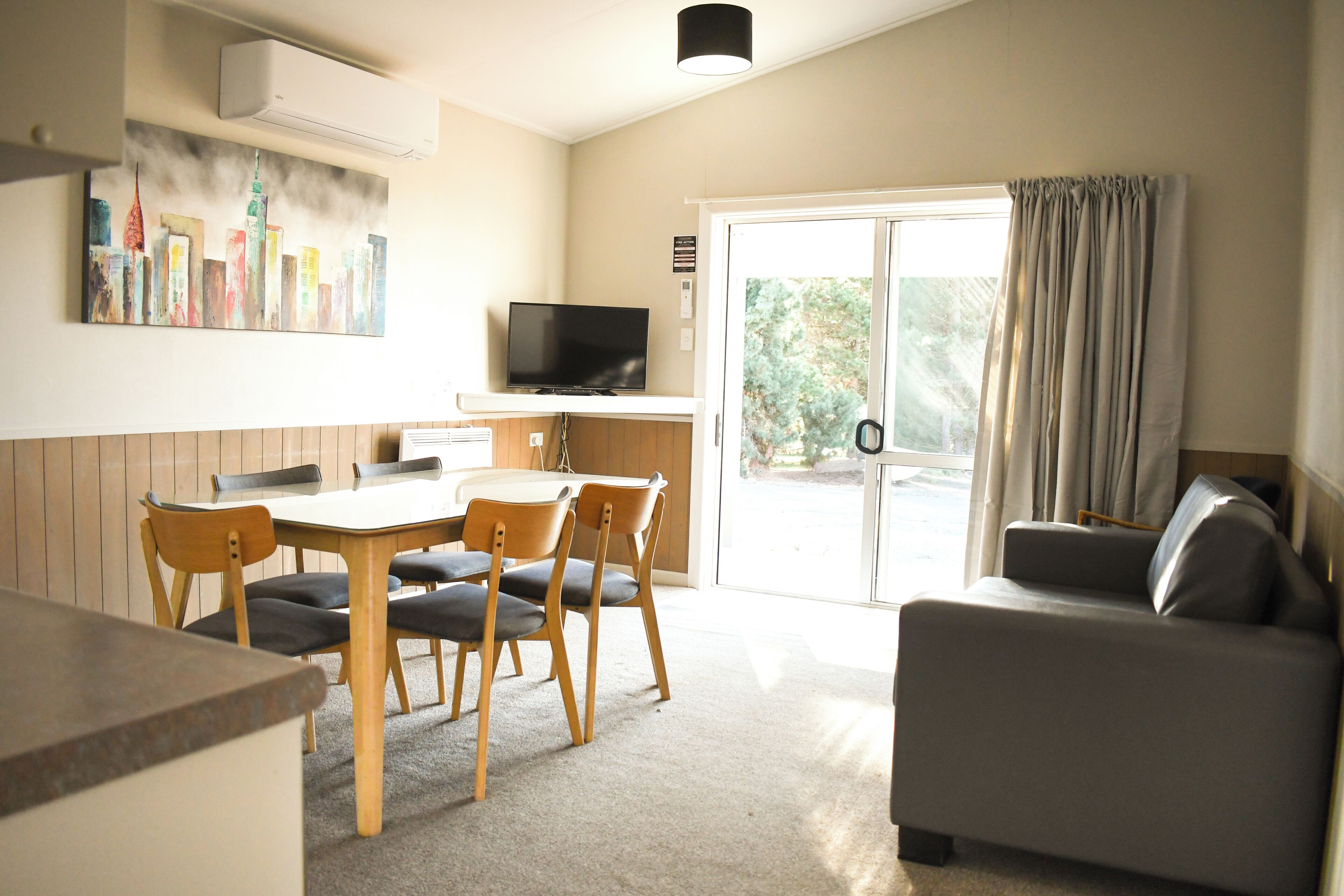 A living room with a television, a dining area with a table and chairs, and a sofa.