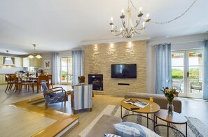 Relax in this spacious living room with a large flat-screen TV, dining area, and comfortable seating.