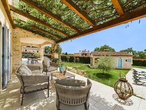 Relax in a serene, shaded retreat with a casual dining or lounging area, complete with a lantern and wicker seating.