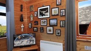 A room with wooden walls, a television displaying a space-themed movie, and various framed pictures on the wall. - Private Star Wars themed lodge with lovely views (Arisaig)