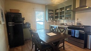 Une cuisine de taille réduite comprenant un coin repas, un réfrigérateur, une cuisinière et une fenêtre.